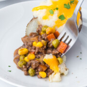 Half of a Shepherds Pie Baked Potatoes cut open to show the ground meat filling and mashed potato topping