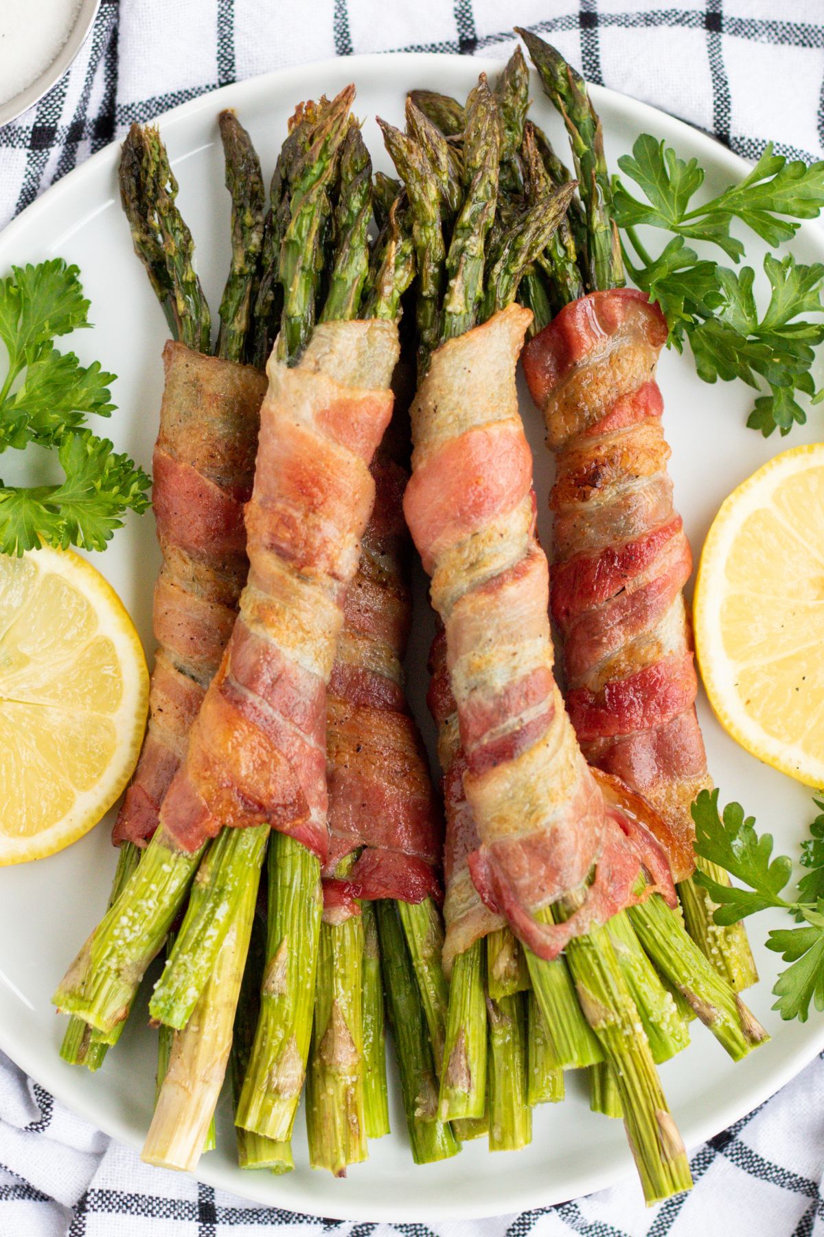 A bunch of asparagus wrapped in bacon on a plate.
