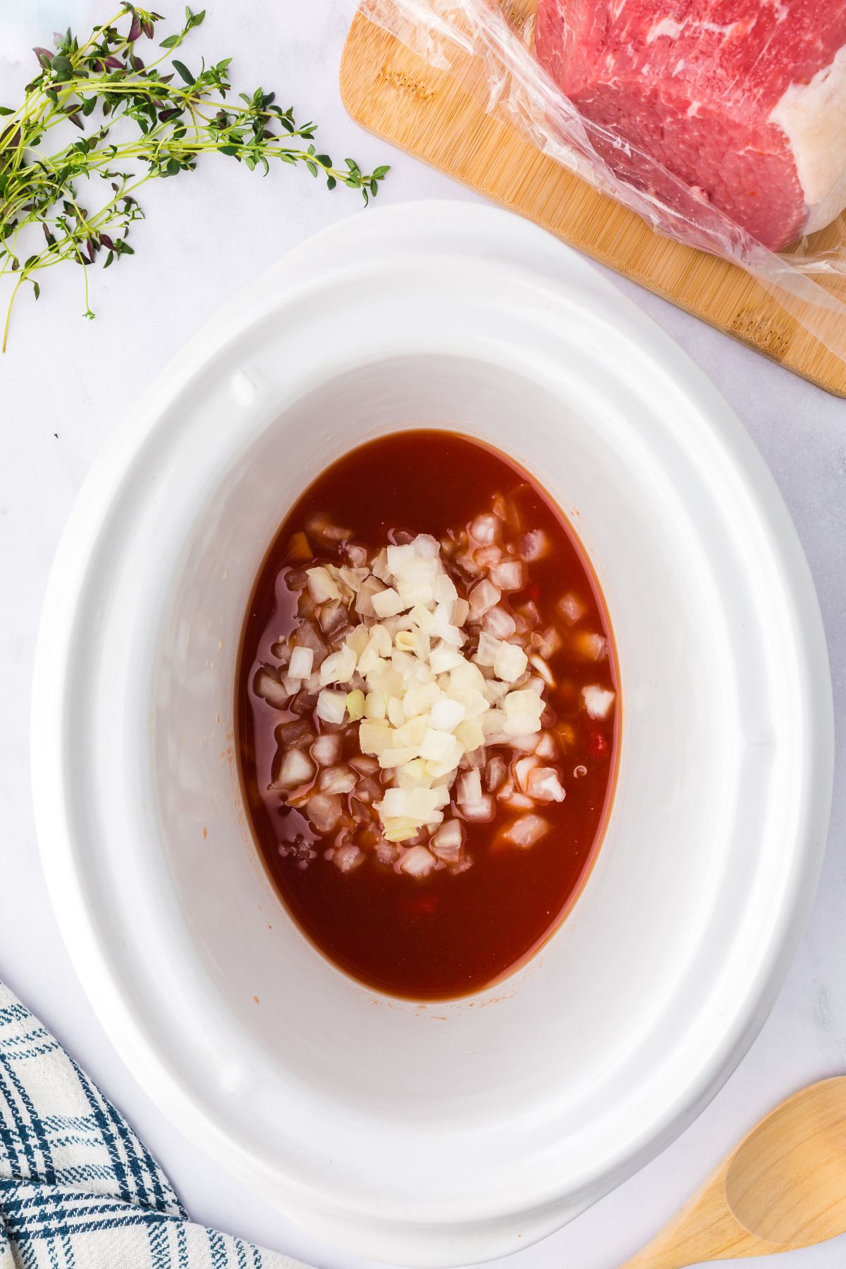 Onions added into the crockpot with the broth and tomato paste.