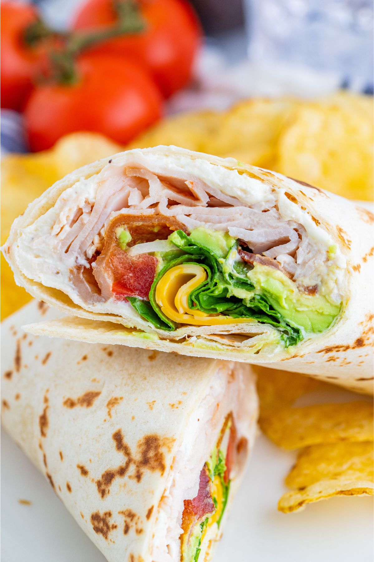 Two halves of a turkey club wrap on a plate.
