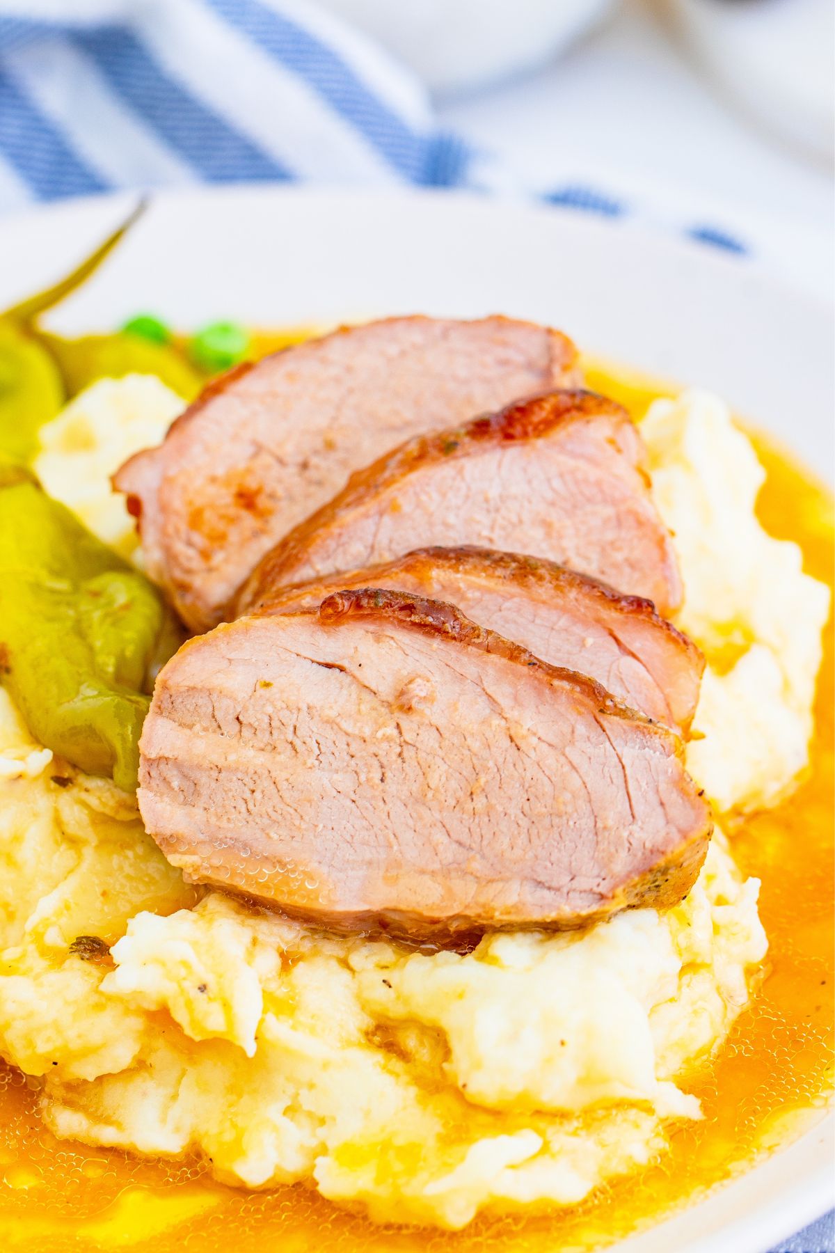 Four slices of pork tenderloin over mashed potatoes and sauce.