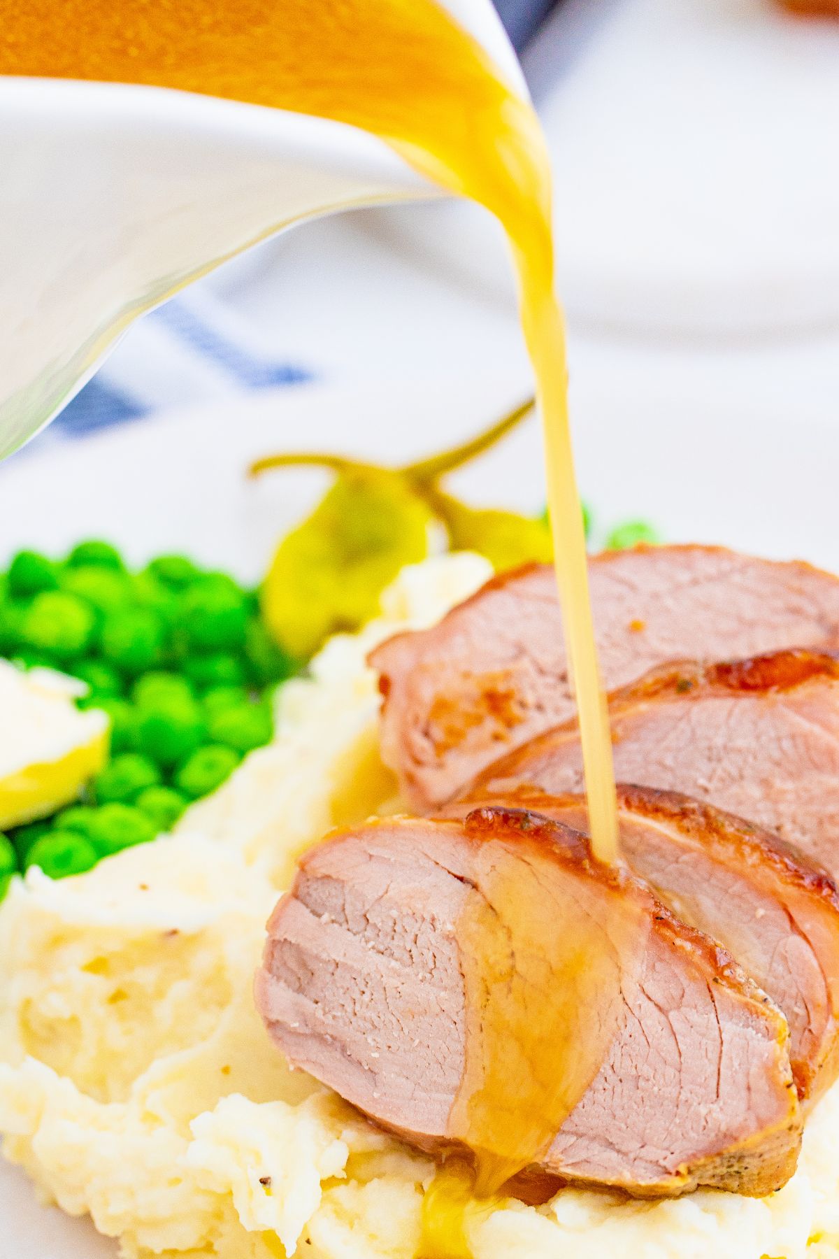 Pouring gravy over slices Mississippi pork tenderloin.