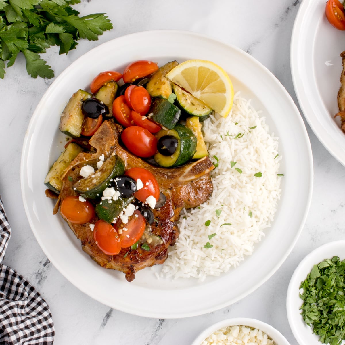 Bowl of Easy Greek Pork Chops with rice and salad 