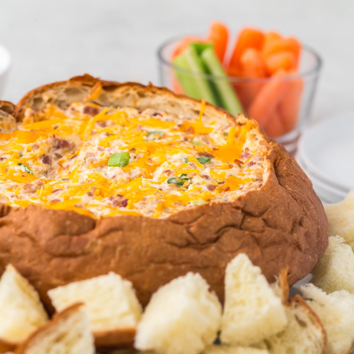 Cheese Bacon Dip inside break bowl with pieces of break scattered around breadbowl