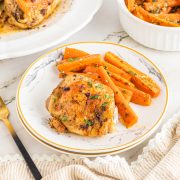 Garlic chicken thigh on a white plate with carrots.