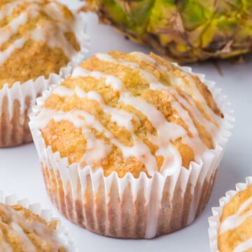 A glazed pineapple muffin on a counter with others.