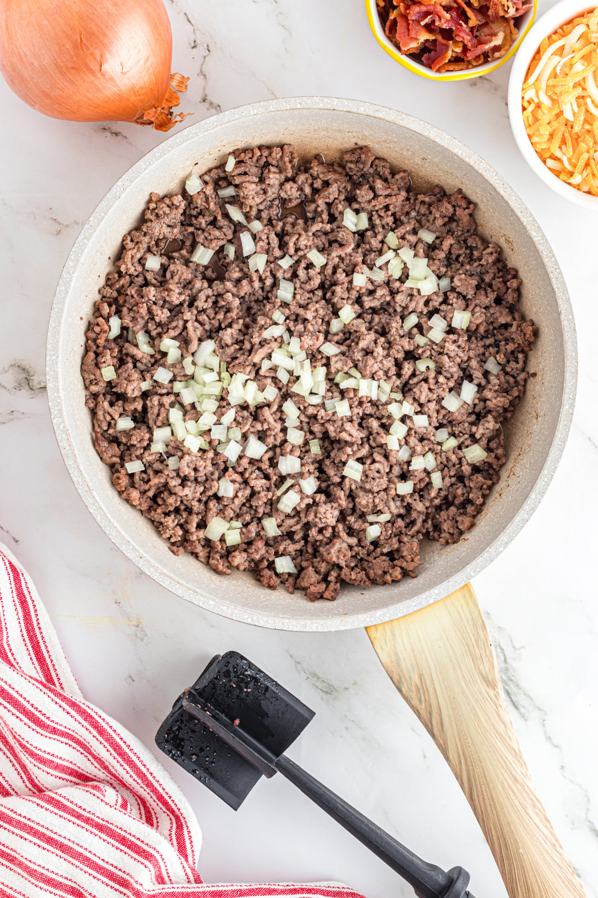 Ground beef and onions cooking in a skillet.
