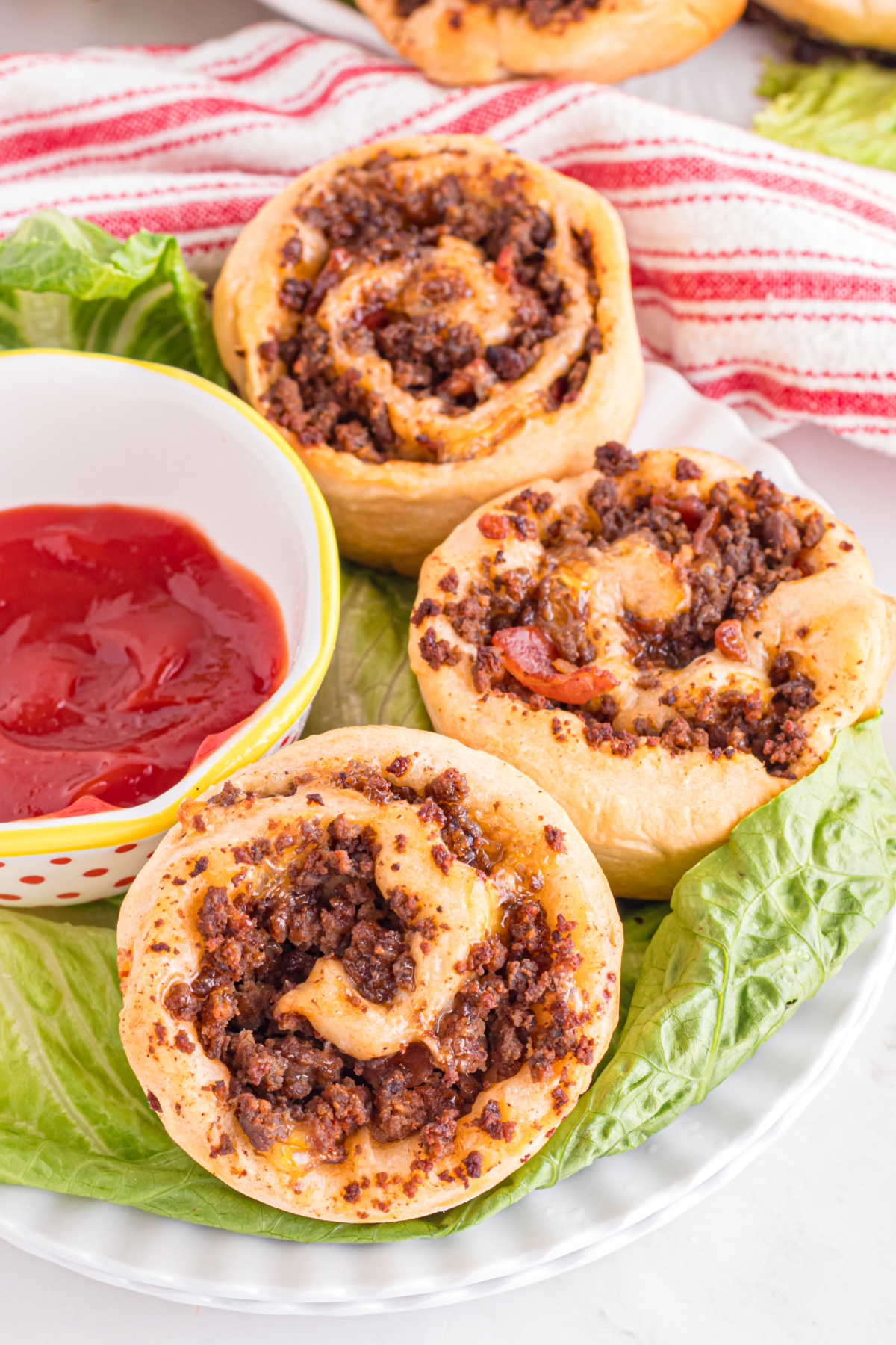 Three hamburger pinwheels on a bed of lettuce.