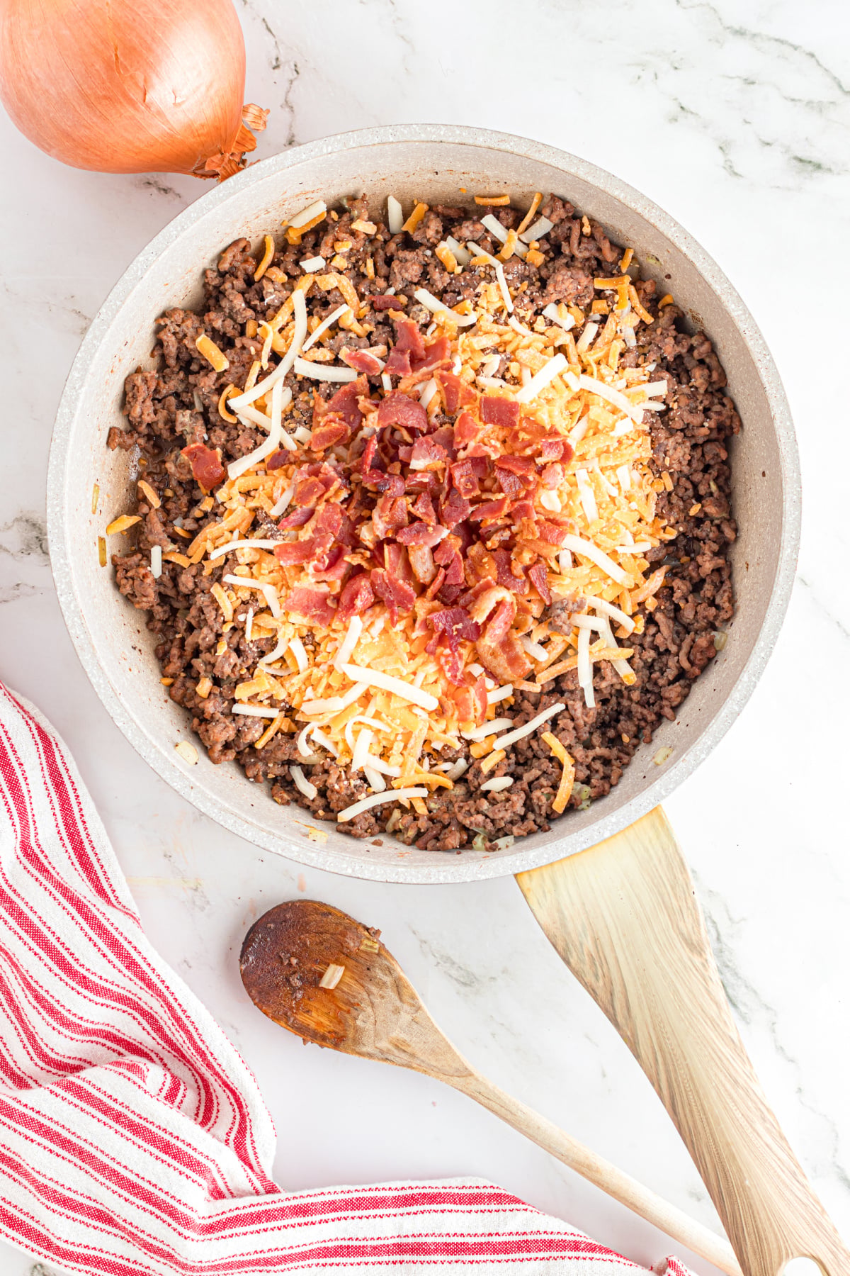 The condiments, cheese, and bacon added to the ground beef.