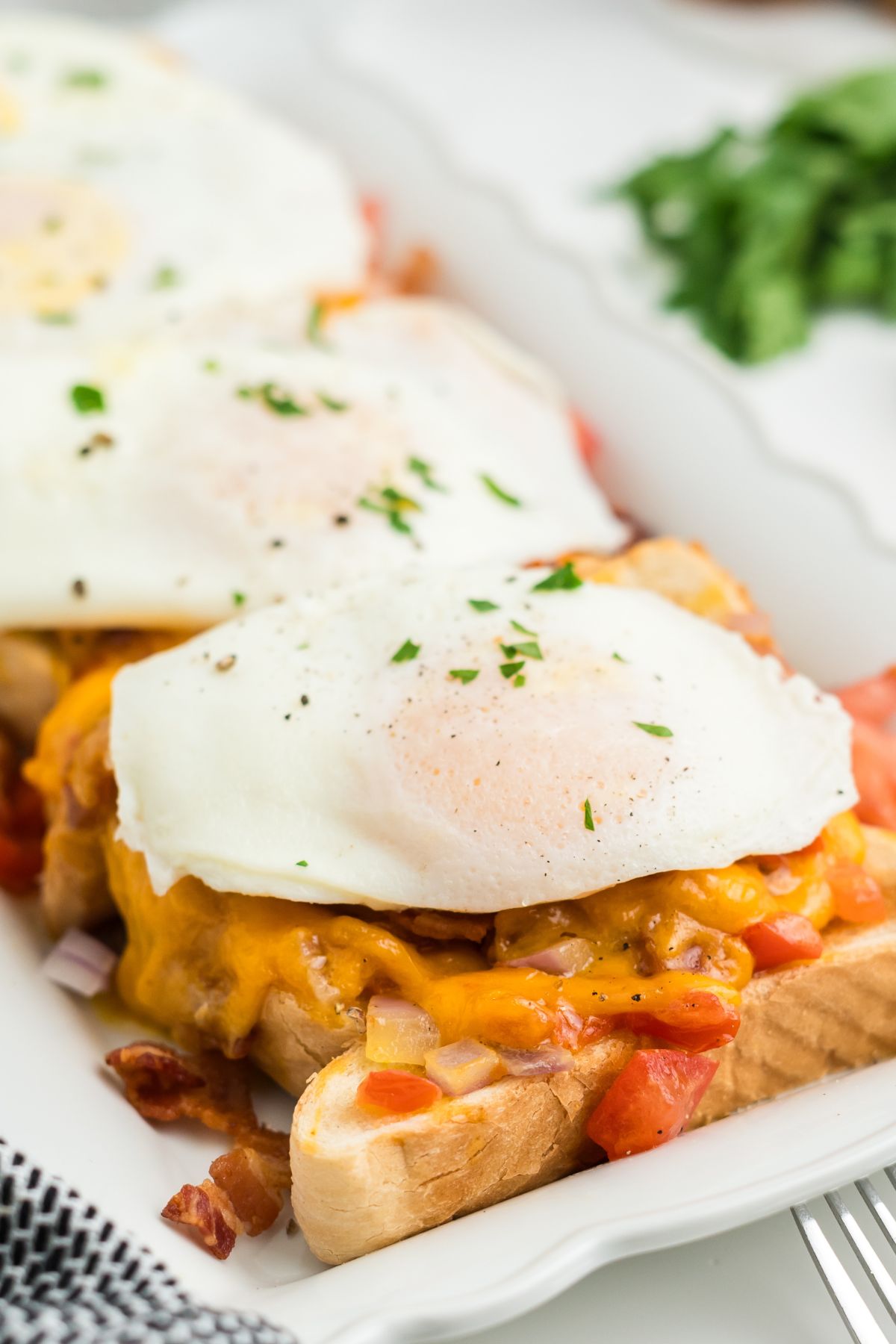 A slice of toast with cheese, veggies and an over easy egg on top.