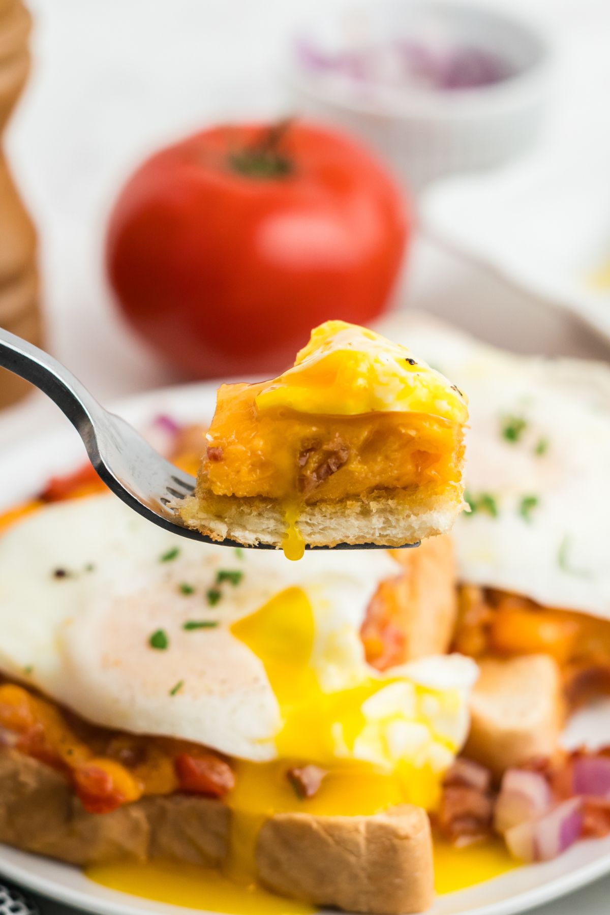 A fork lifting up a bite of the egg, cheese, and toast.