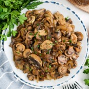 Asian mushrooms on a round serving plate topped with chopped parsley.