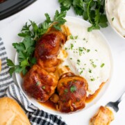 Crockpot BBQ chicken thighs on a plate with mashed potatoes.