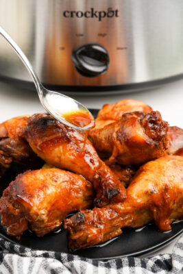 Drizzling sauce over the honey chicken drumsticks.