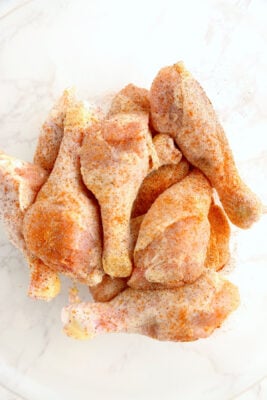 Chicken in a bowl with seasoning added.