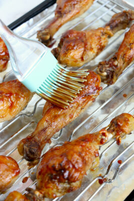Brushing sauce on chicken drumsticks.