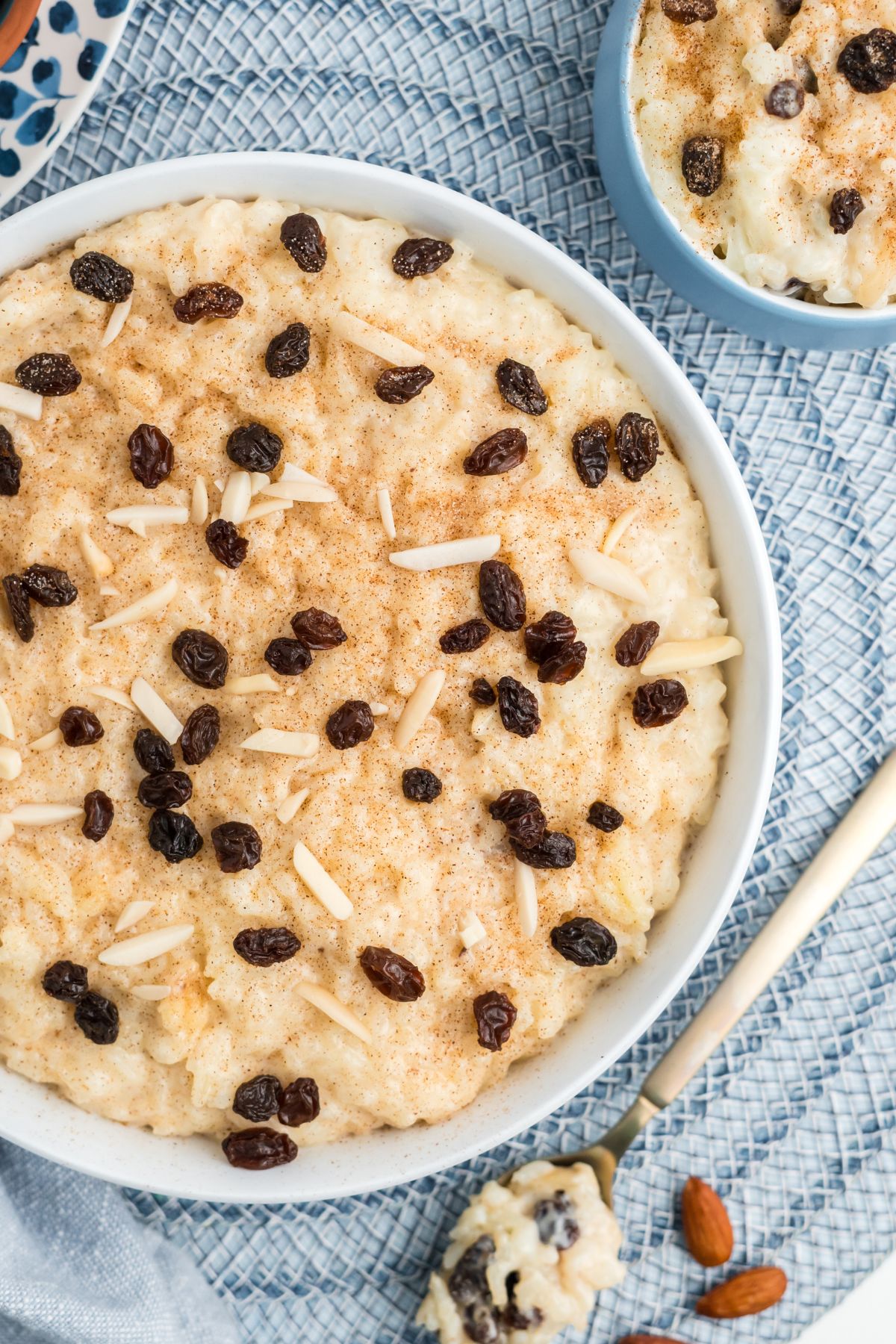 Rice pudding with raisins and almonds on top in a white bowl.
