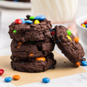 Four chocolate M & M cookies in pile with one leaning on side.
