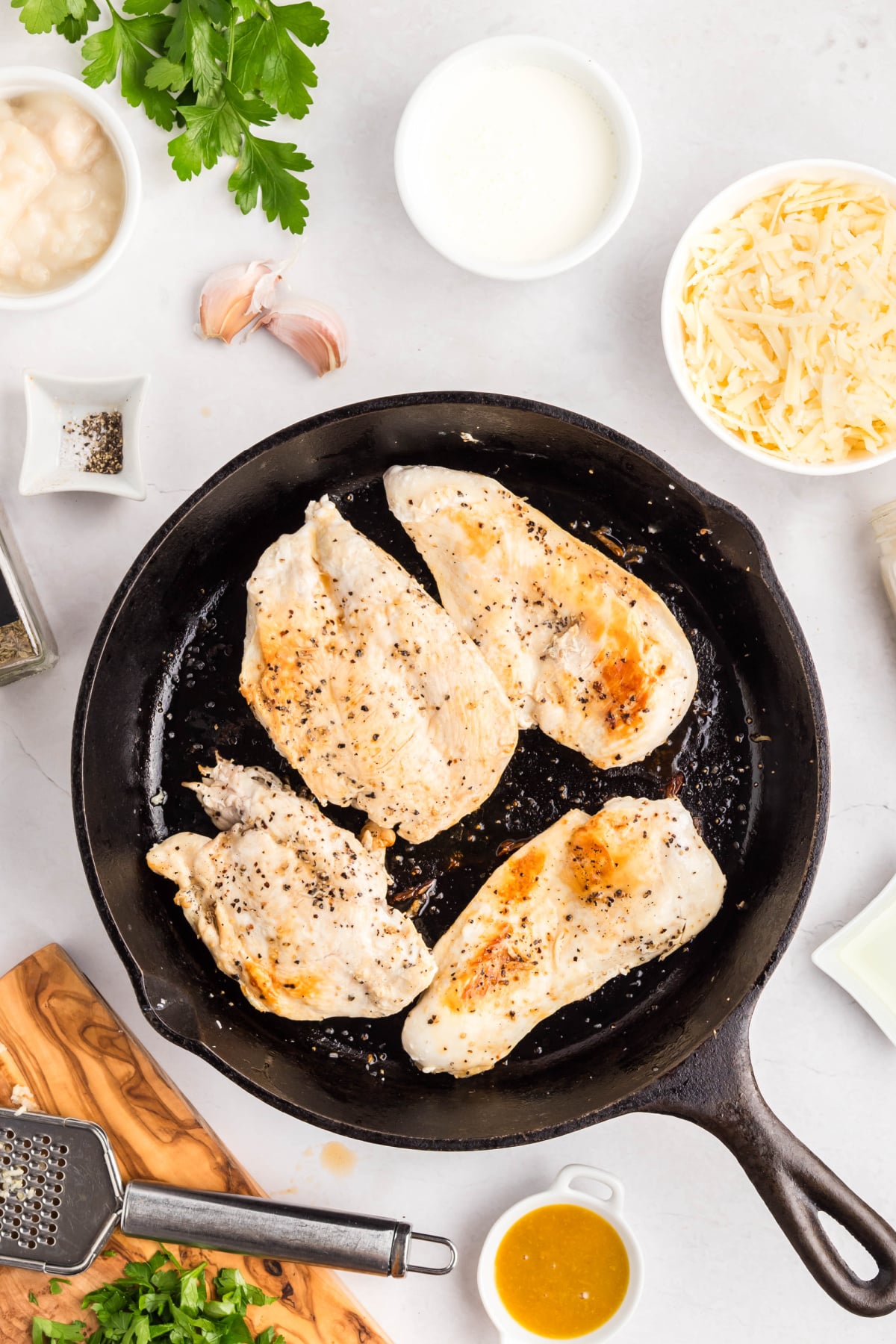 Seasoned chicken breast in a skillet cooking.