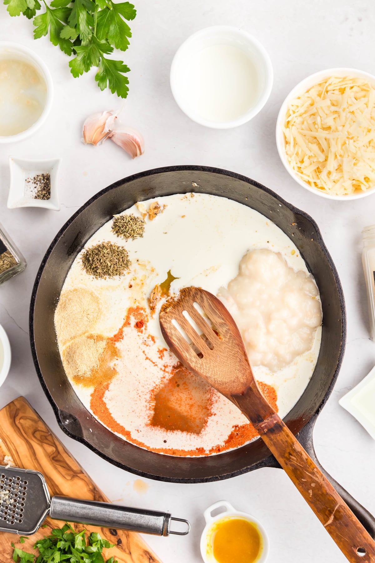 The garlic, bouillon, stock, cream, spices, and soup added to the skillet.