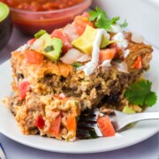A slice of Mexican breakfast casserole with a fork taking off a piece from the front.