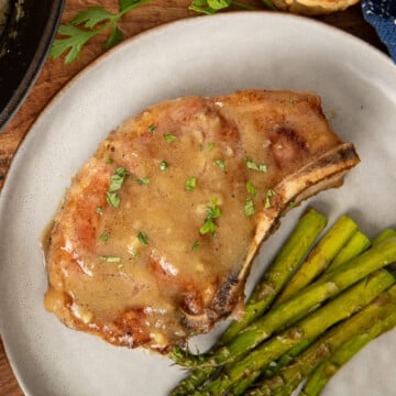 Honey Mustard Pork Chops served coated in sauce on plates with asparagus.