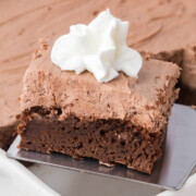 Bailey’s cheesecake brownies in a dish with a slice held up on a spatula.