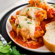 Three baked stuffed shells on a plate.