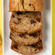 A loaf of my favorite chocolate chip banana bread with a few slices cut and leaning over.