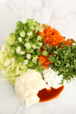 Mayonnaise, cilantro, green onions, celery, carrots, sour cream, and hot sauce in a large mixing bowl.