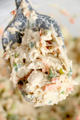 Shredded chicken mixed into mayo mixture on a spoon.