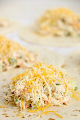 Shredded cheese on top of chicken in the tortilla.