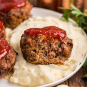 Meatloaf muffins on a plate with one missing a bite.