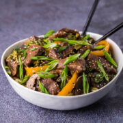 Slow cooker beef tips and vegetables in a white bowl with sticks.