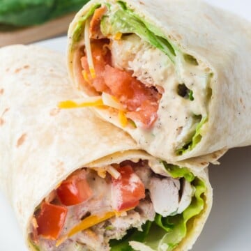 Chicken ceasar wrap cut in half on a plate.