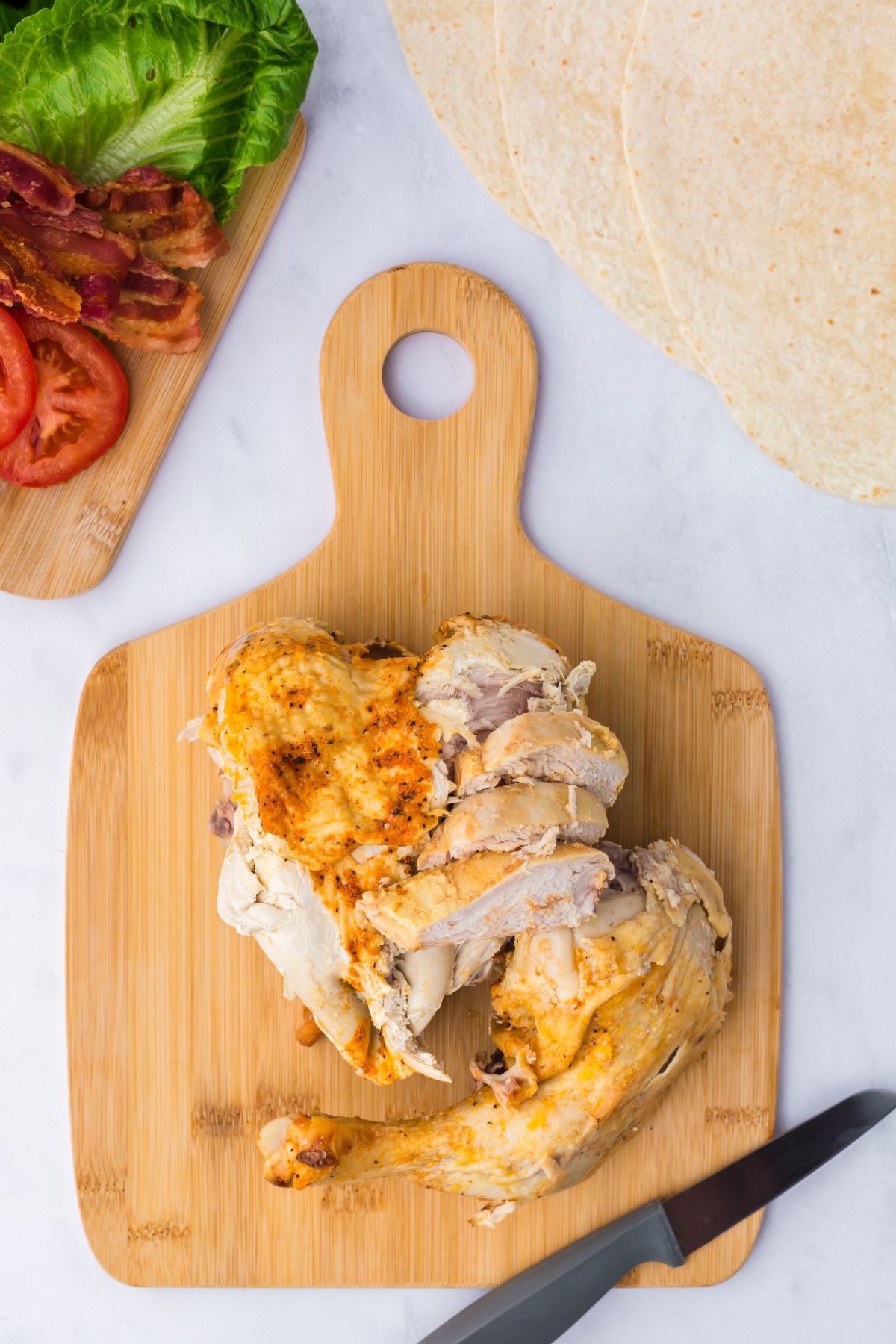 Cooked chicken cut up, skinned and debones on a cutting board.