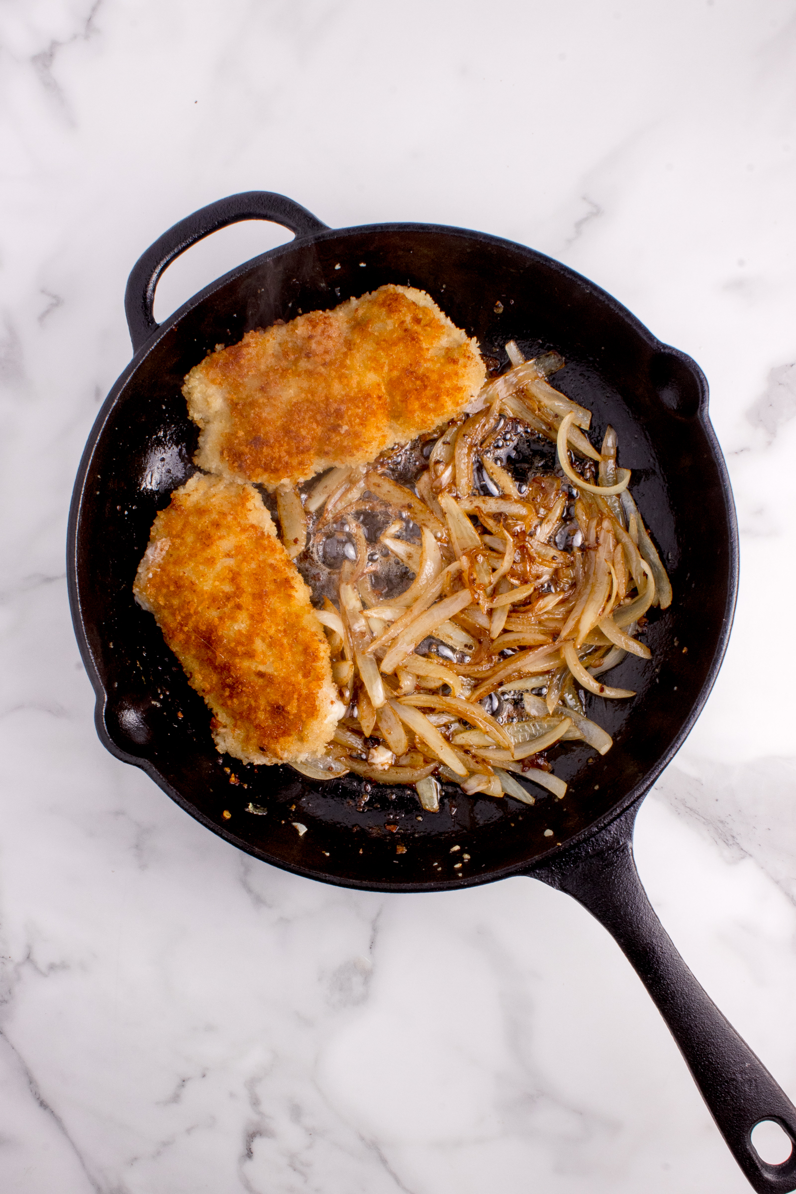 Veal added to the onions and garlic sauted in a cast iron skillet.