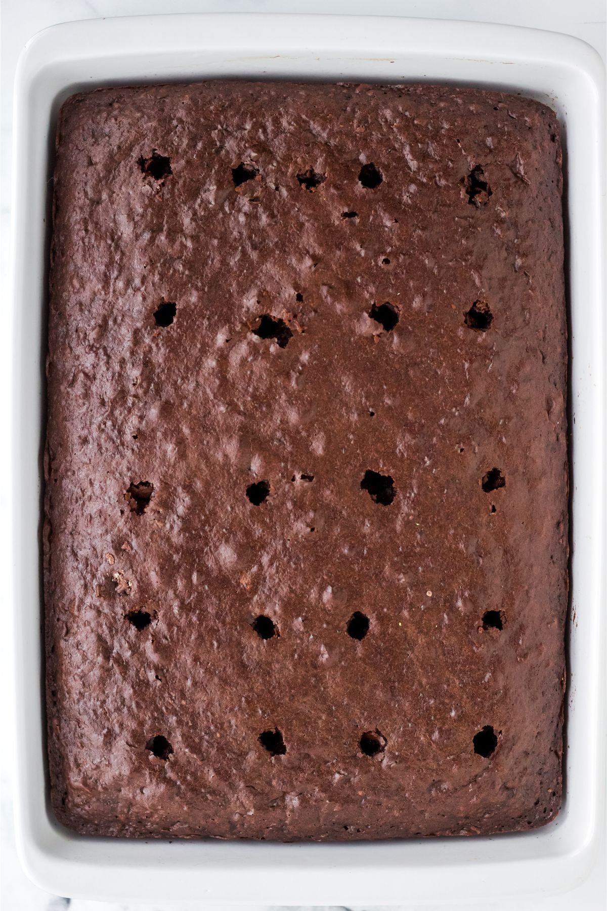 Chocolate cake cooled in a baking dish with holes.