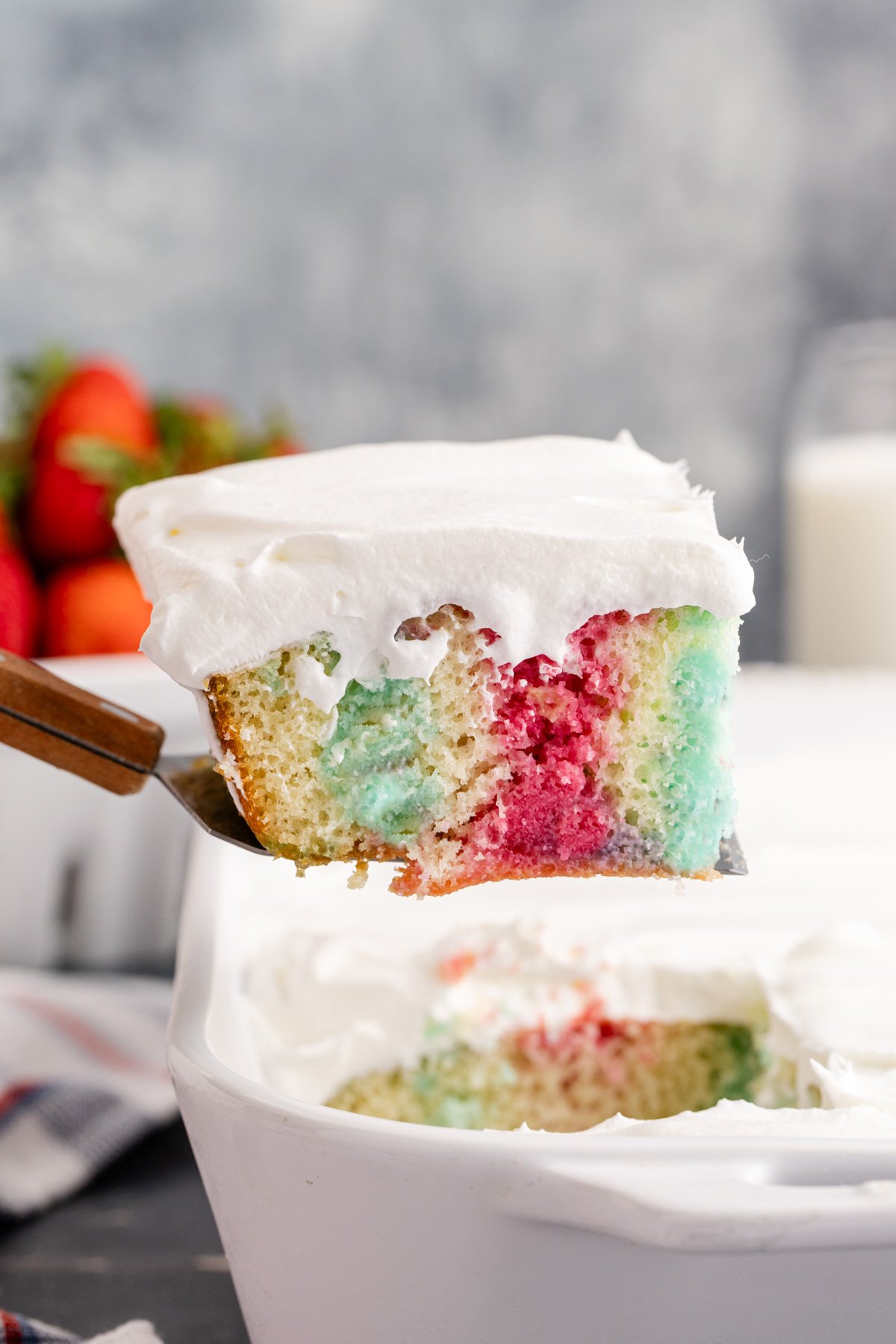 A slice of poke cake held up with a serving spoon.