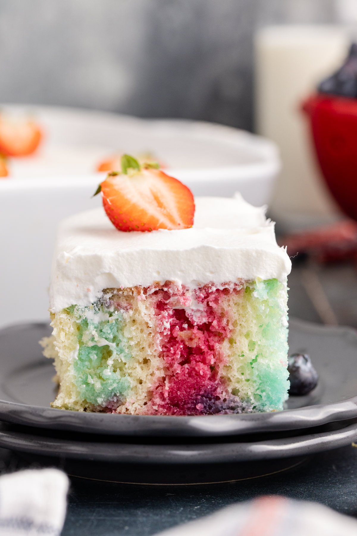 A slice of jello poke cake on a black plate.