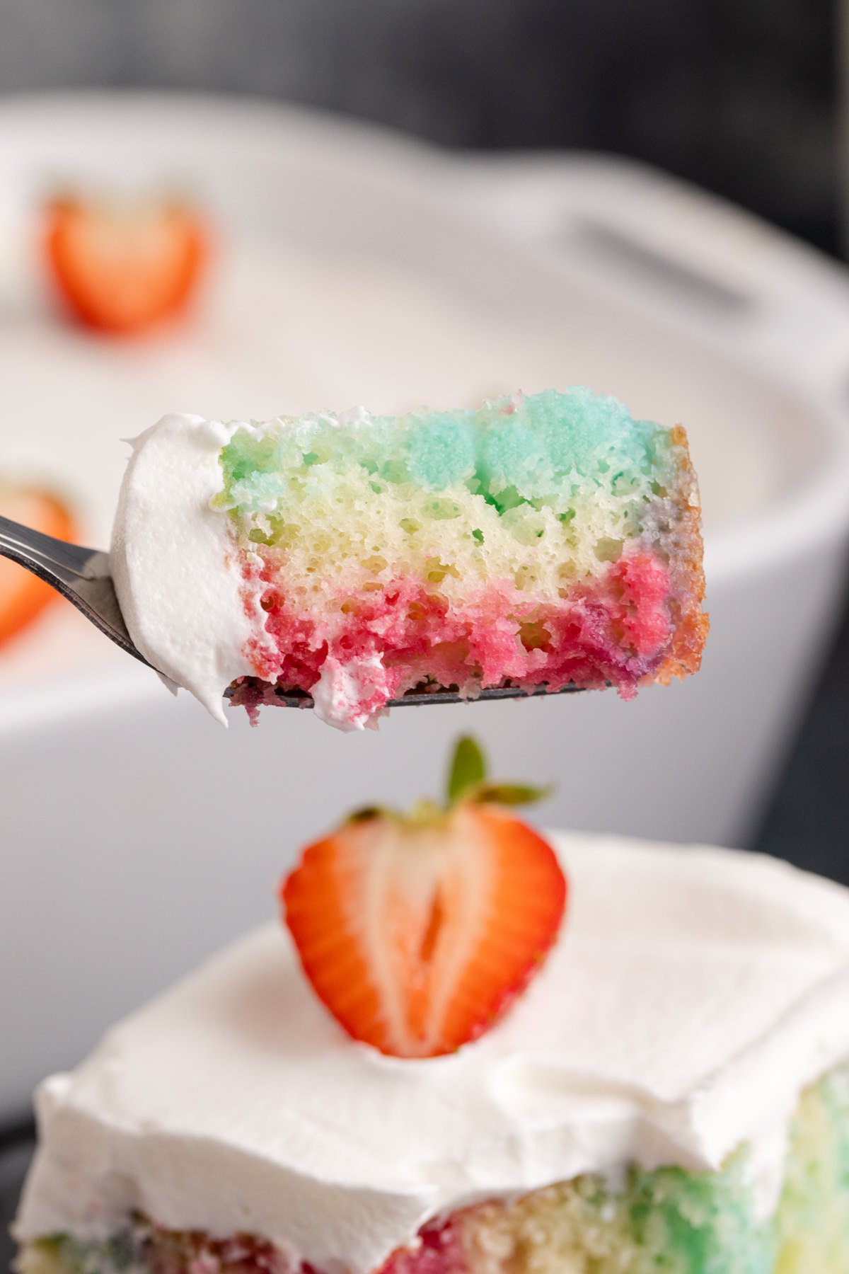 A piece of Jello poke cake on a fork being held up in the air.