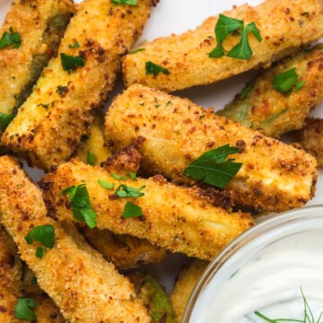 A plate full of zucchini fries with dip.