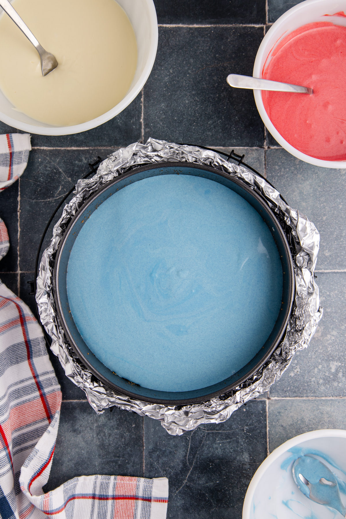 Blue cheesecake batter in a springform pan.