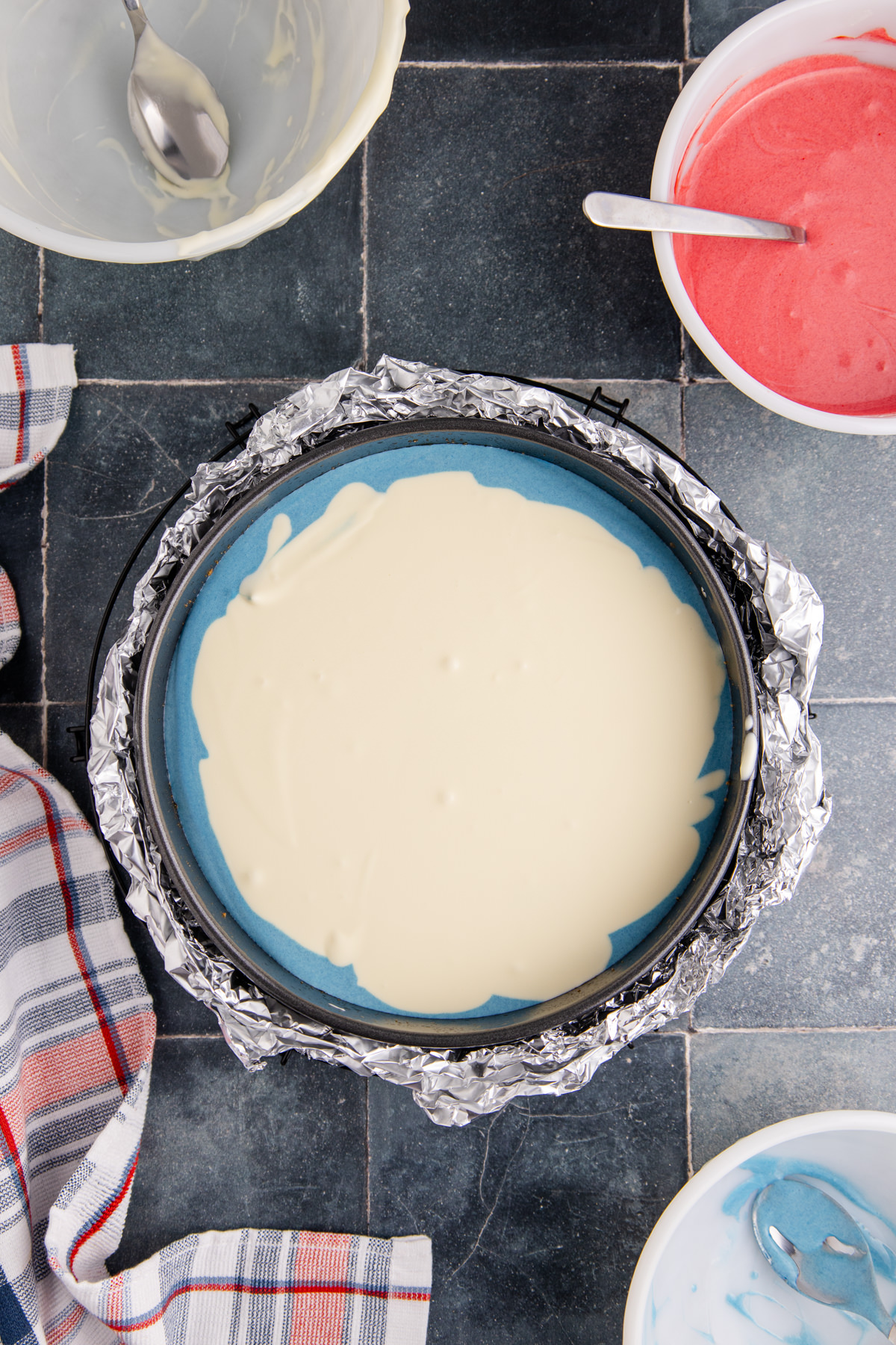 White color poured into the blue cheesecake batter in a springform pan.