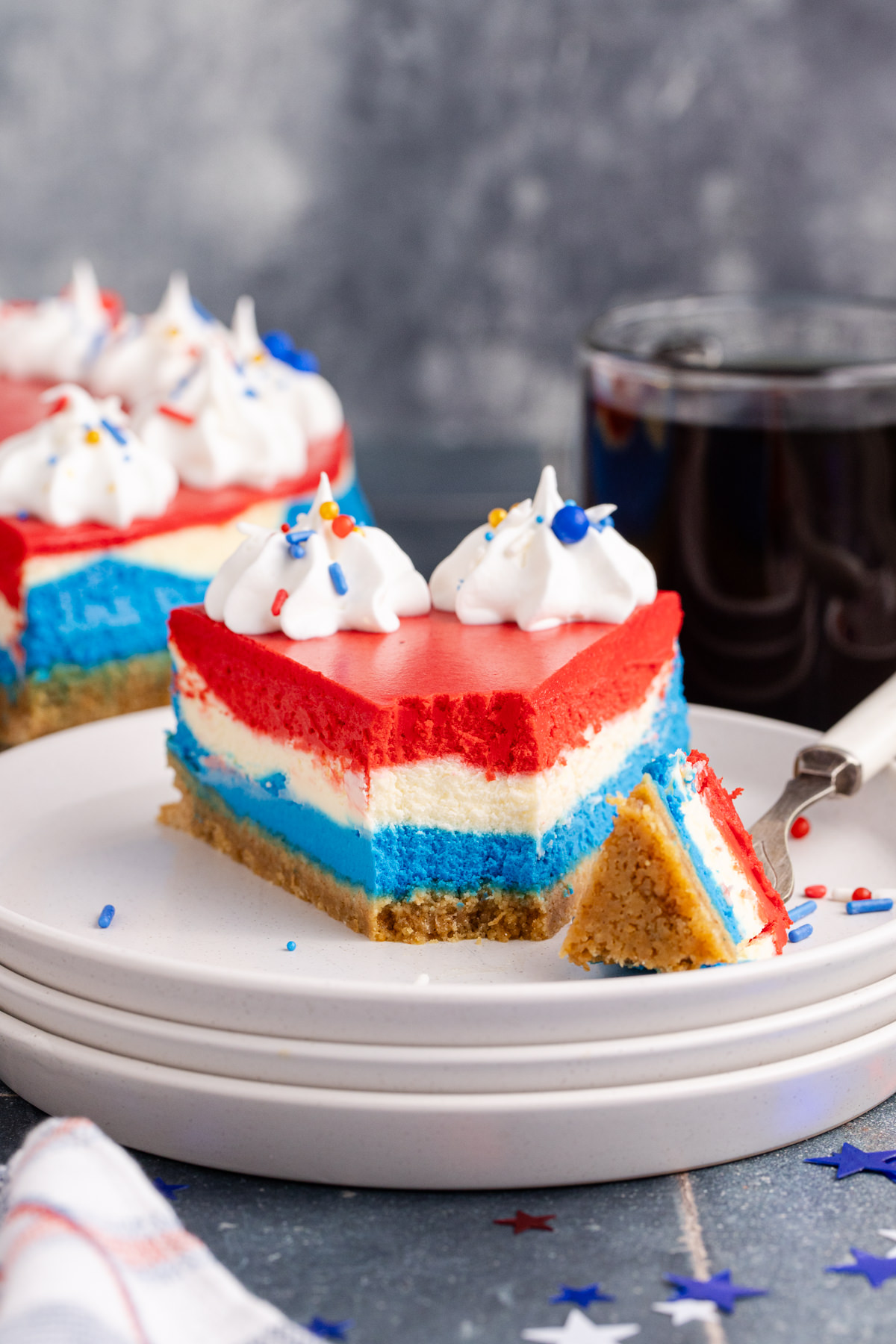 A slice of layered cheesecake with a piece taken out with a fork.