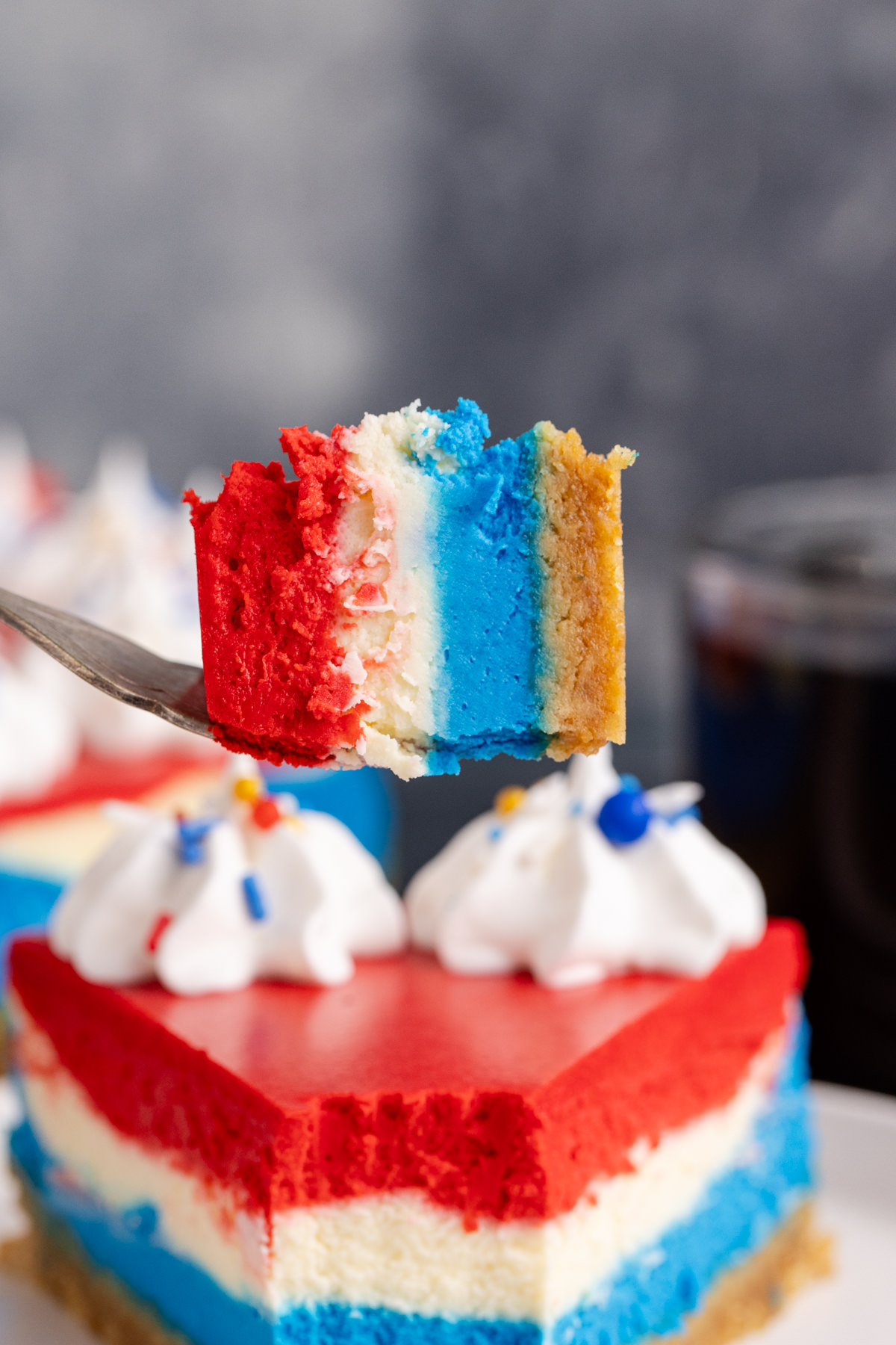 A bite of red, white, and blue cheesecake on a fork.