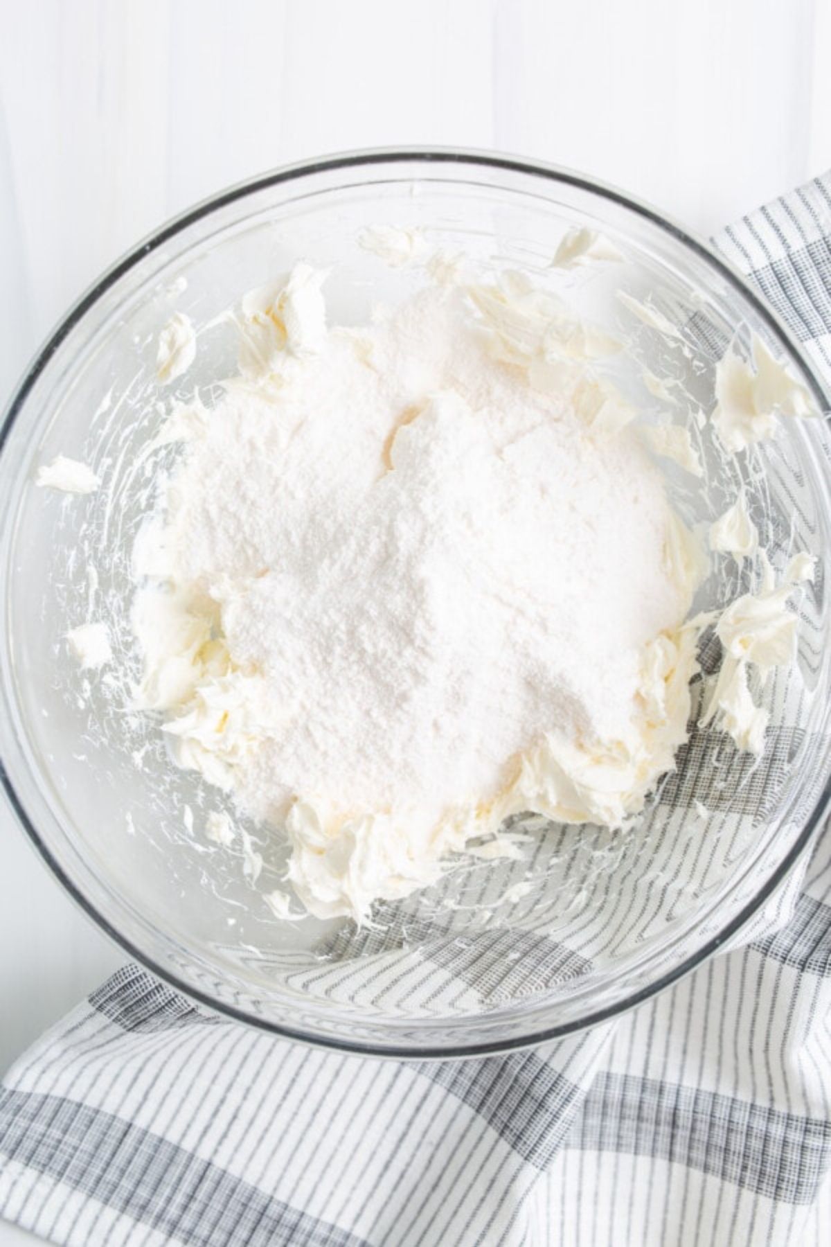 Cream cheese whipped in a bowl topped with powdered sugar.