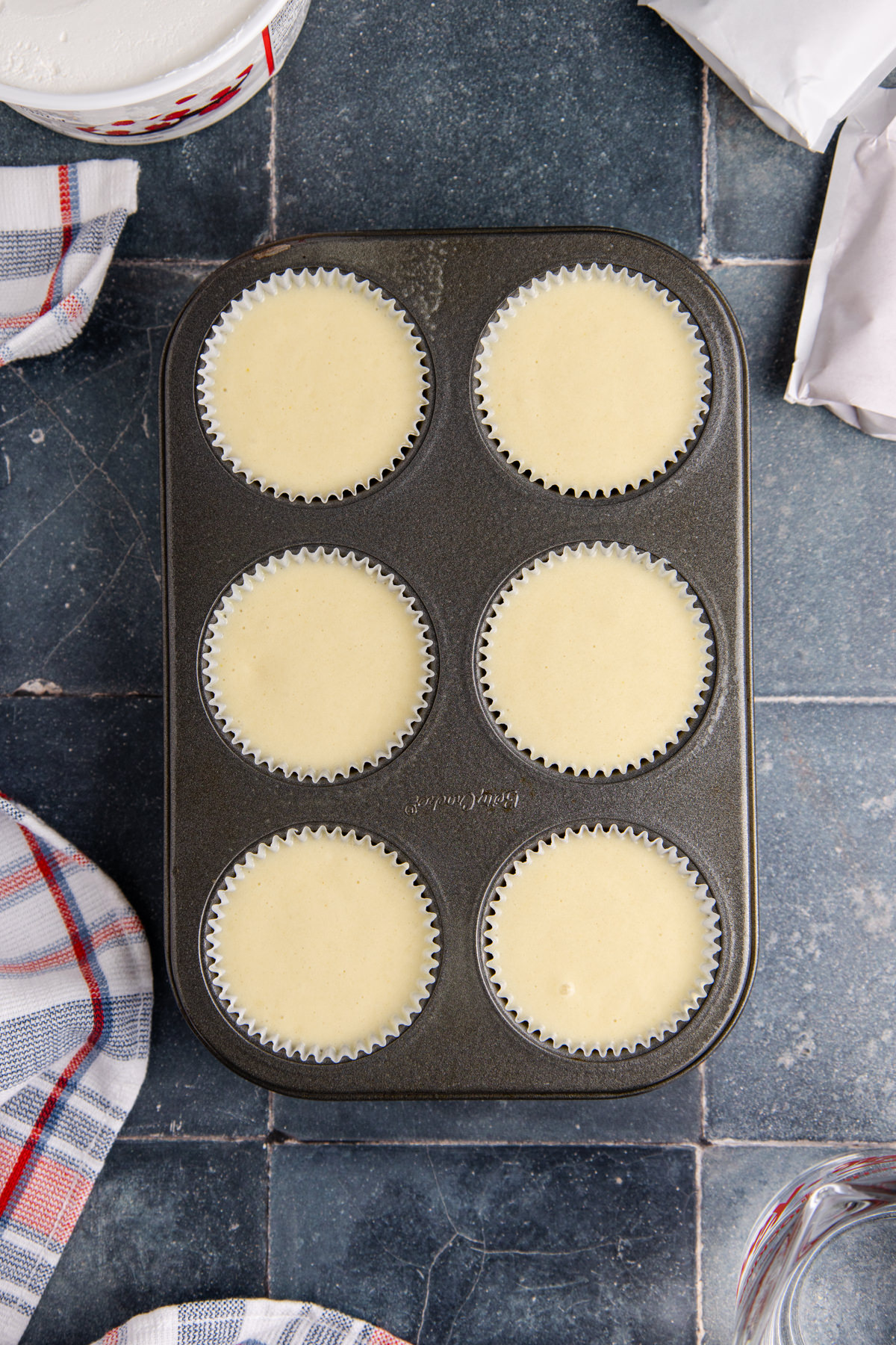 A scoop of batter in each liner in the cupcake pan.