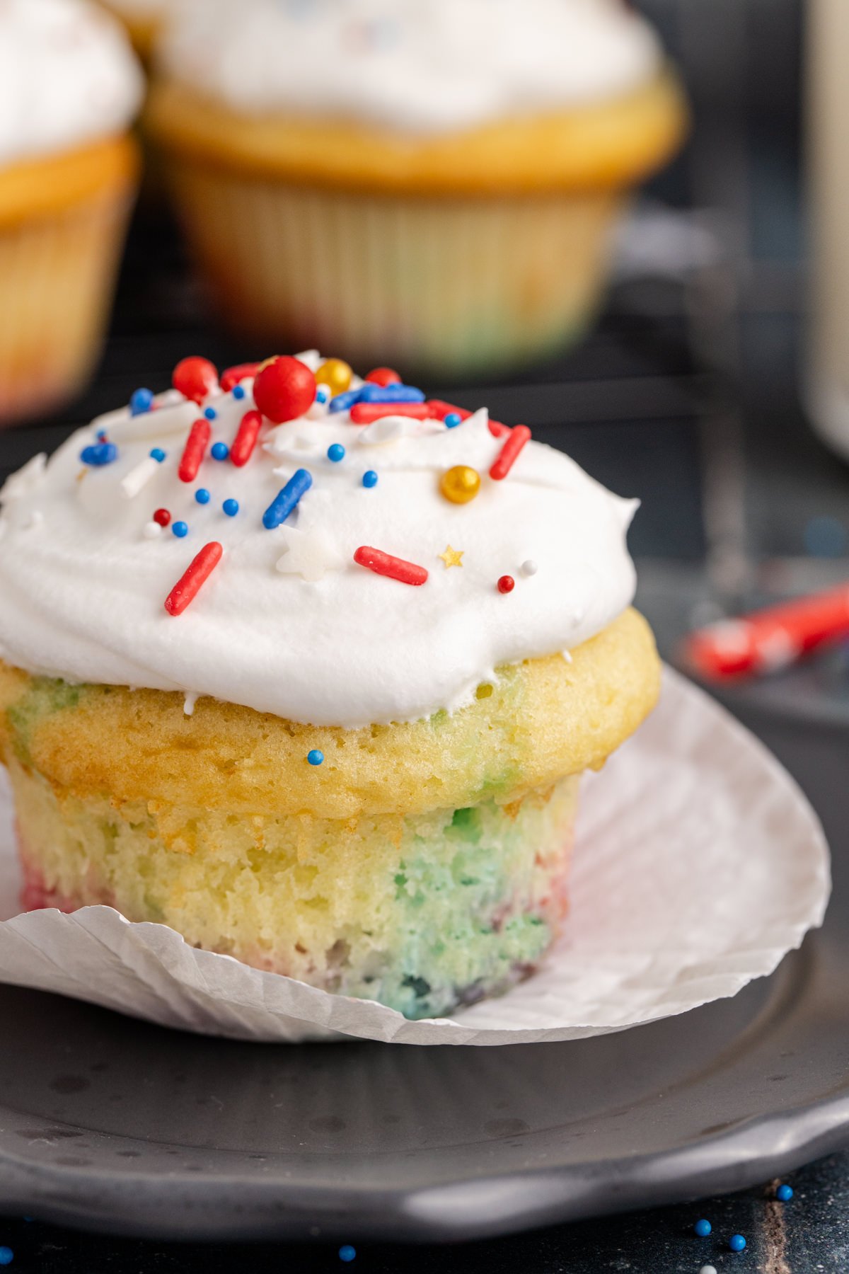 Unwrapped cupcake with red, white and blue sprinkles.