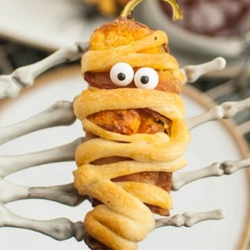 Jalapeno popper mummies with a skeleton hand holding one.